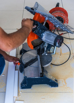 Closeup view of a man that is cutting wooden board electric circular saw. Focus is on the tools