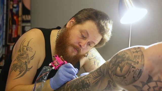 Close up tattoo artist demonstrates the process of getting black tattoo with paint.