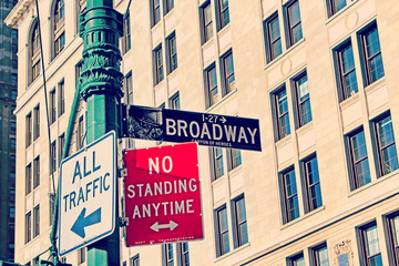 Obraz premium Broadway Street Signs with brick building in soft focus in the b