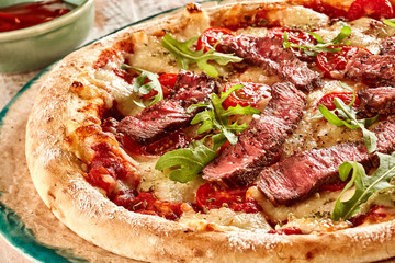 Rare beef slices and arugula on pizza