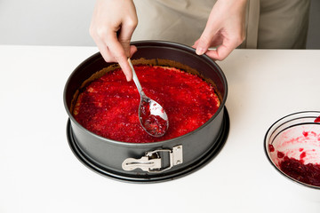 Eine Frau bereitet eine Torte mit Himbeermarmelade auf