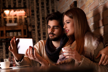 Beautiful young couple looking at tablet in cafe.