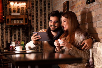 Beautiful young couple looking at tablet in cafe.