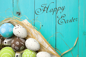 Easter card. Painted Easter eggs in a nest on a blue wooden background with copy space for congratulation