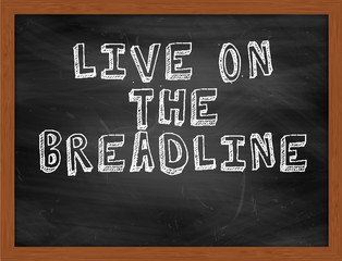 LIVE ON THE BREADLINE handwritten text on black chalkboard