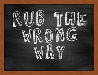 RUB THE WRONG WAY handwritten text on black chalkboard