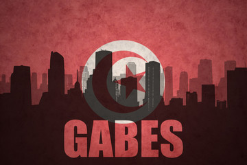 abstract silhouette of the city with text Gabes at the vintage tunisian flag
