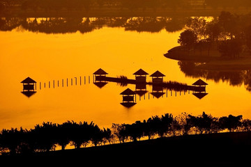 Silhouette of a house and a tree in the water.