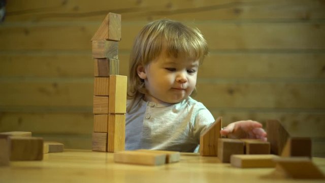 A blond baby boy focus on wooden blocks