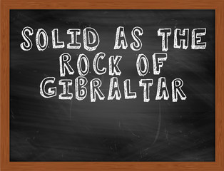SOLID AS THE ROCK OF GIBRALTAR handwritten text on black chalkbo