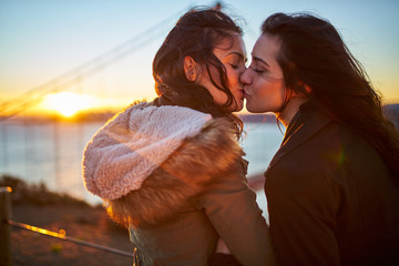 romantic lesbian couple kissing at golden gate bridge - obrazy, fototapety, plakaty
