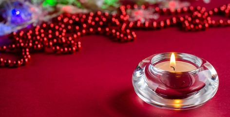 Burning candle on red background.