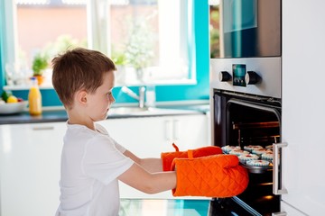 Child holding baking tray with cupcakes