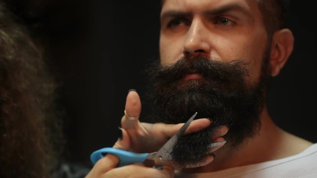 bearded man going through before beard haircut by hairdresser at barbershop