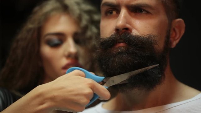 Beautiful fashionable female barber cutting and handsome man with long beard