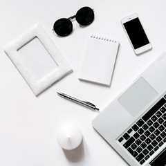 White office desk with laptop, smartphone and notebook . Top view with copy space, flat lay.
