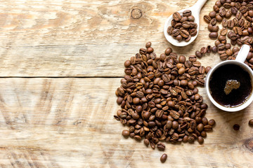 cup of coffee, beans and spoon on wooden background