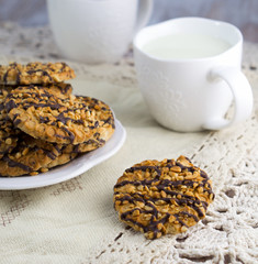Chocolate and nuts ship cookies on a saucer, a cup of milk, clos