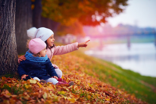 two beautiful girls sitting in autumn park