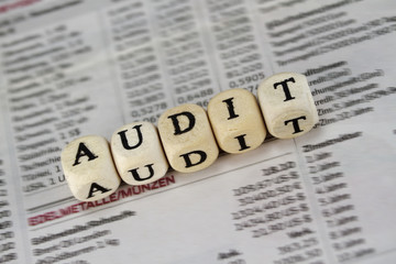 Audit word built with letter cubes on newspaper background
