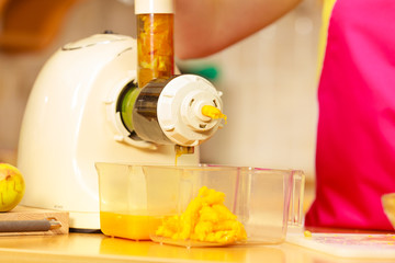 Making orange juice in juicer machine in kitchen