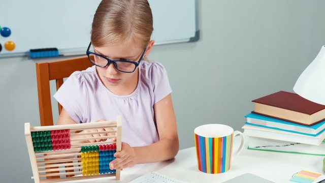 Portrait student girl 7-8 years using abacus in her desk at home. Zooming