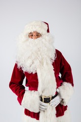 Santa Claus in eyeglasses and red costume standing on white background and looking into camera. American shot
