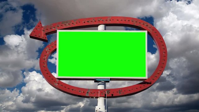 Vintage arrow sign with chroma green insert and time lapse clouds.