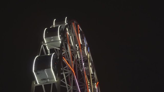 Ferris wheel rotating at amusement park under dark night sky