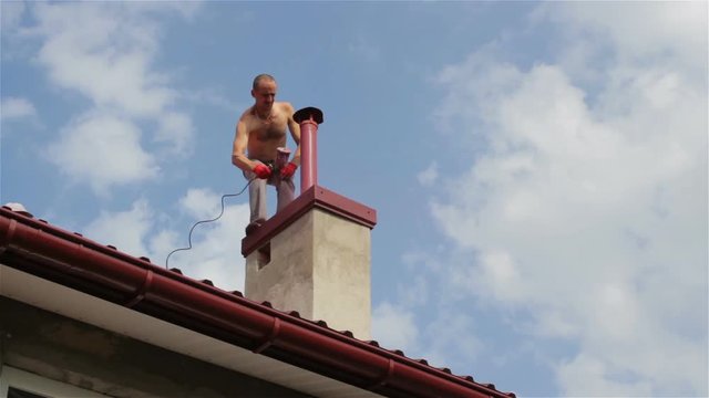 painting chimney/man paints a chimney pipe on a roof