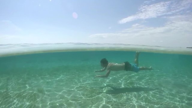 UNDERWATER: Happy young guy swimming underwater and exploring amazing ocean