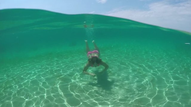 UNDERWATER: Beautiful girl with long brown hair swimming underwater in ocean