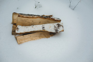 the stack of the snowy firewood on old wooden background.