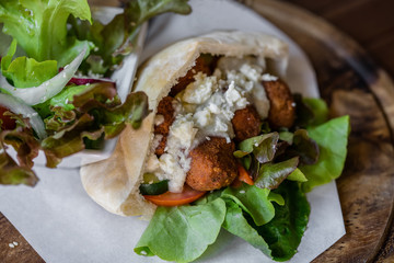Falafel and fresh vegetables in pita bread on wooden table