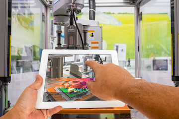 Industry 4.0 and Augmented reality for industry concept. Hand holding tablet with A/R manufacturing system control application on automate machine in smart manufacturing background.
