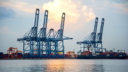 Obraz premium Container Cargo freight ship with working crane bridge in shipyard at dusk for Logistic Import Export background, select focus