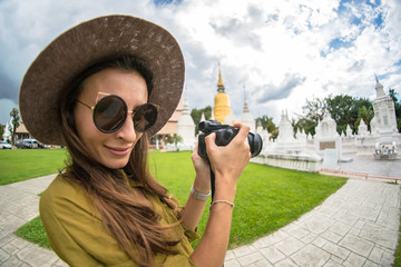 The beautiful girl a blyunetka in a green shirt and a hat in sunglasses, photographs monuments in Thailand, the tourist

