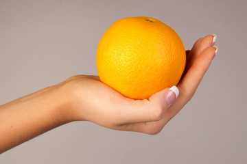 Woman's hand holding an orange