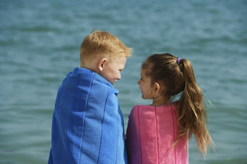 Fototapeta na wymiar boy and girl at beach, wrapped in towels