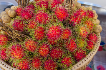 Red rambutan Nephelium lappaceum on broun wicker basket.