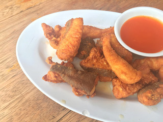 Horizontal photo of closeup fried fish with chili sauce on wooden background.