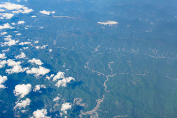 Small clouds floating above misty aerial view of mountain range