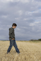 Naklejka na ściany i meble Profile of young man walking in wheat field