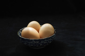 Three brown eggs in blue patterned bowl