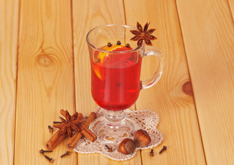 Mulled wine with orange, cloves, anise, cinnamon on light wood.