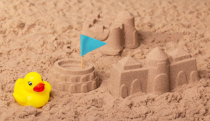 Obraz na płótnie Canvas Castles and Coliseum with flag, rubber duck in sand.