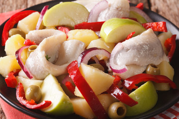 salad of marinated herring with potatoes, green apple, onion, pepper and olives macro. horizontal