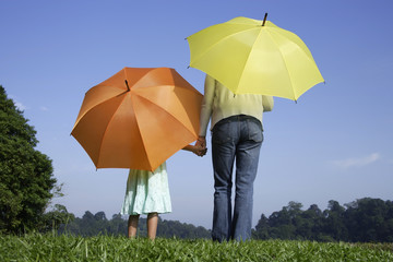 woman and girl standing in front of yellow and orange umbrellas
