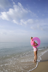 Naklejka na ściany i meble woman at beach with pink tube