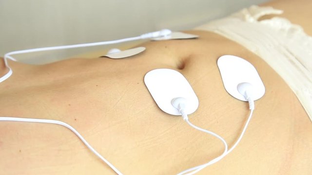 professional electrotherapy on woman body. muscle contraction under the influence of an electric current. close-up patient's stomach